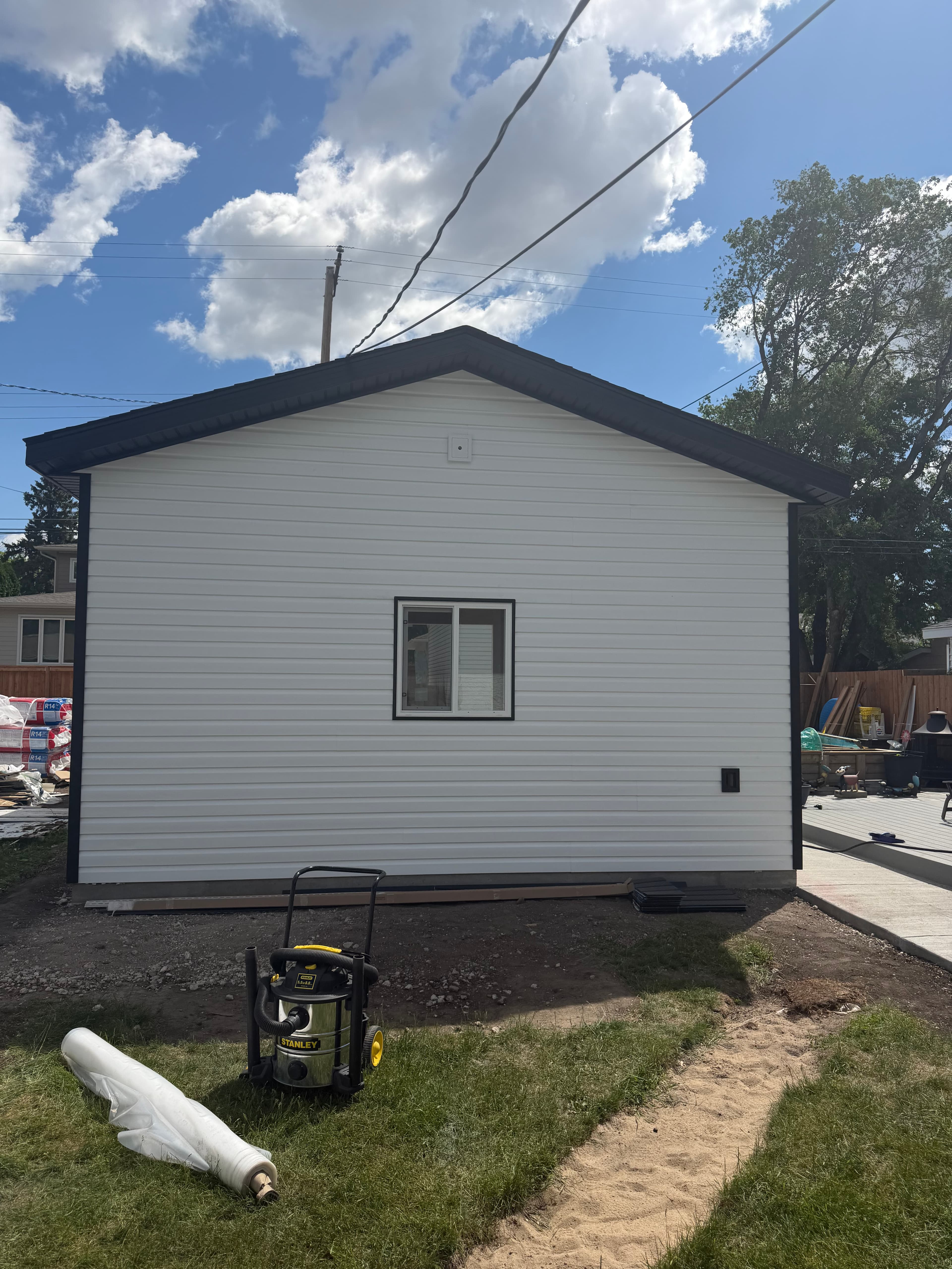White vertical vinyl siding nearly complete on detached garage with window in Saskatoon