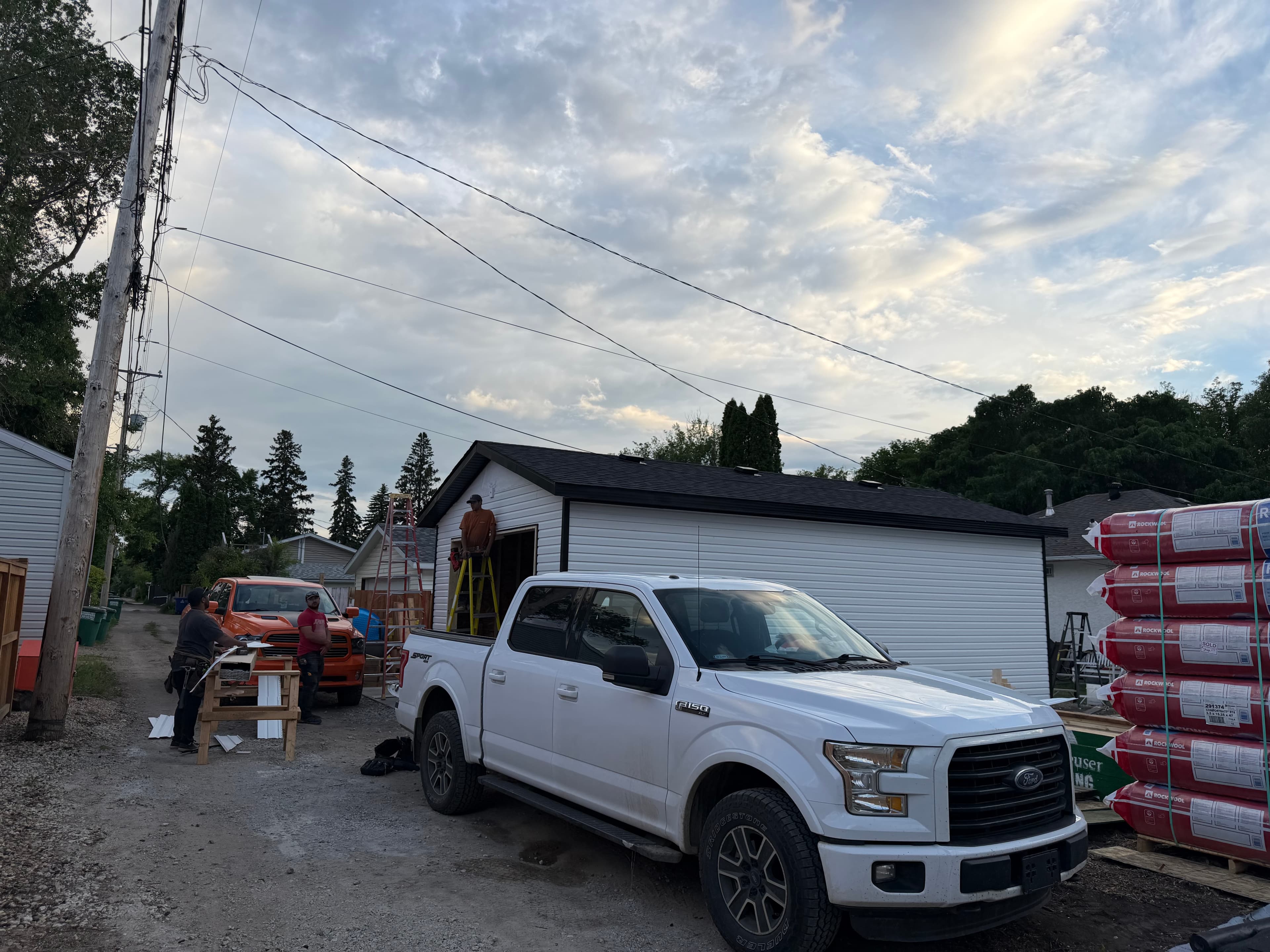 WLG Homes crew with completed detached garage in Saskatoon - white steel siding, dark shingles, dark trim